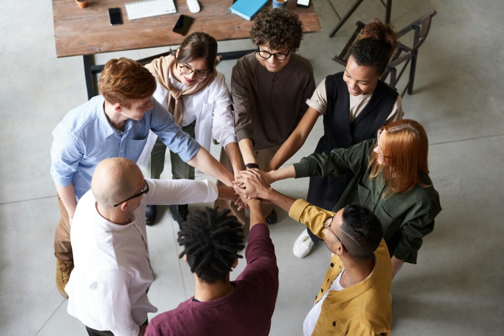 A group of business people put their hands in a pile in the center of a circle