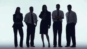 A group of 5 men and women stand in shadow